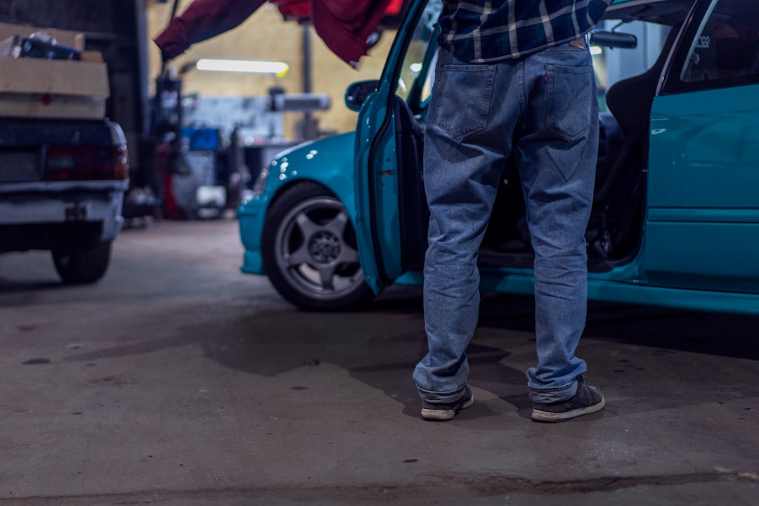 man-in-blue-denim-jeans-and-black-leather-boots-standing-beside-blue-car-during-daytime-xwqywssiseg