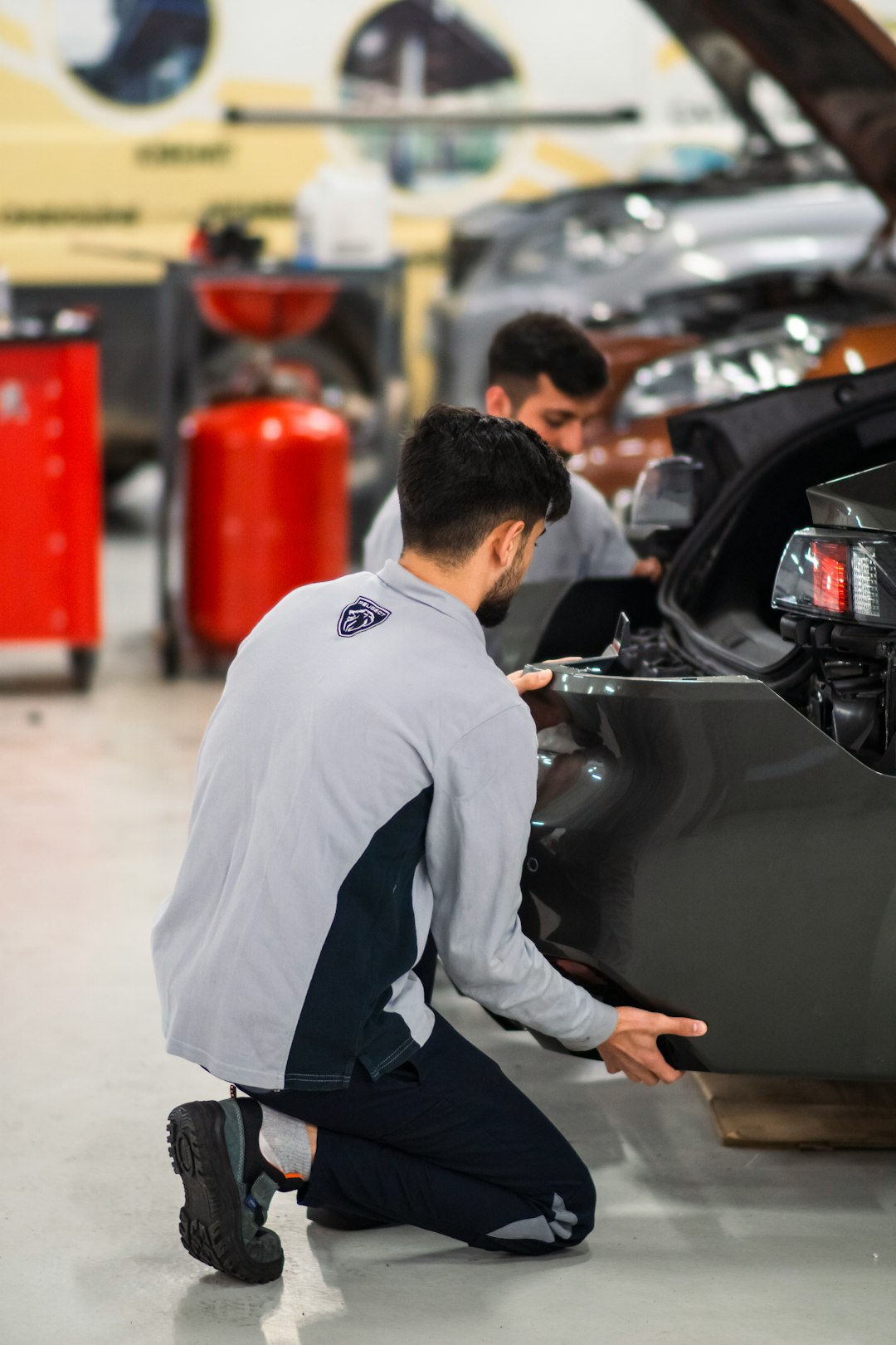 two-men-working-on-a-car-in-a-garage-lf7q1mygtjg