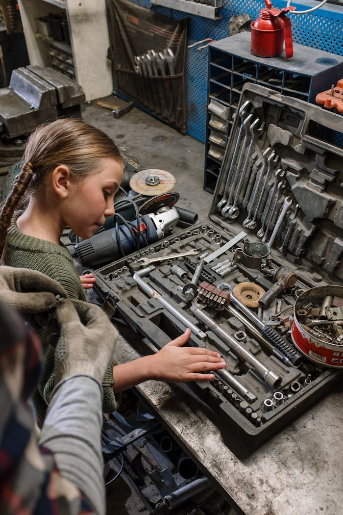 services-02 A girl examines tools in a mechanics workshop, showcasing curiosity and learning about auto repair.